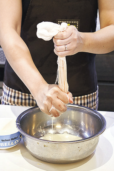 用紗布把打磨的黃豆過濾，隔開豆渣，濾出生豆漿。